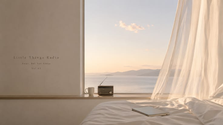 A calm bedroom window open to the sea, with a sheer curtain lifting in the breeze