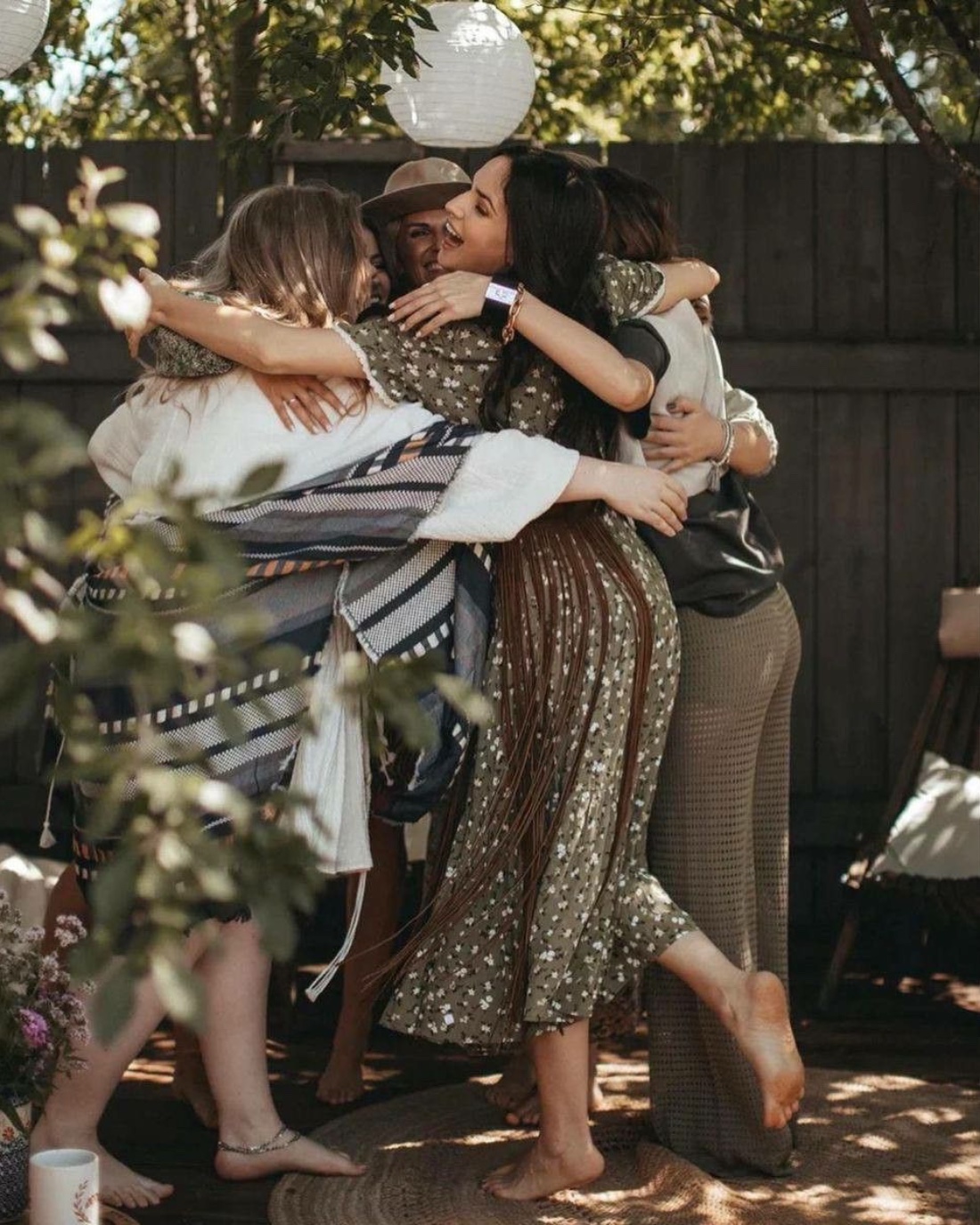 A group of friends embracing in a sunlit backyard