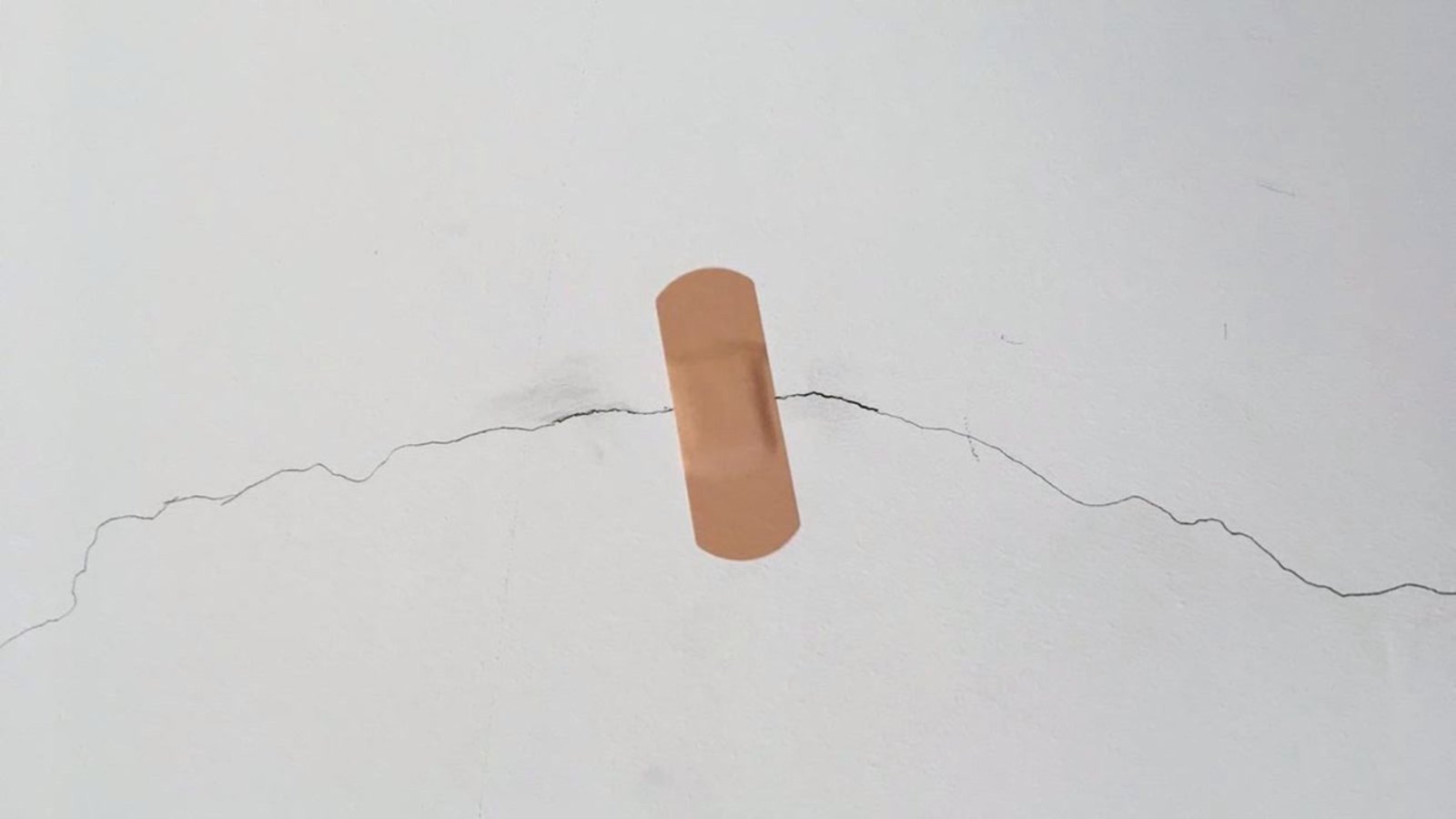 A bandage placed across a crack in a white wall